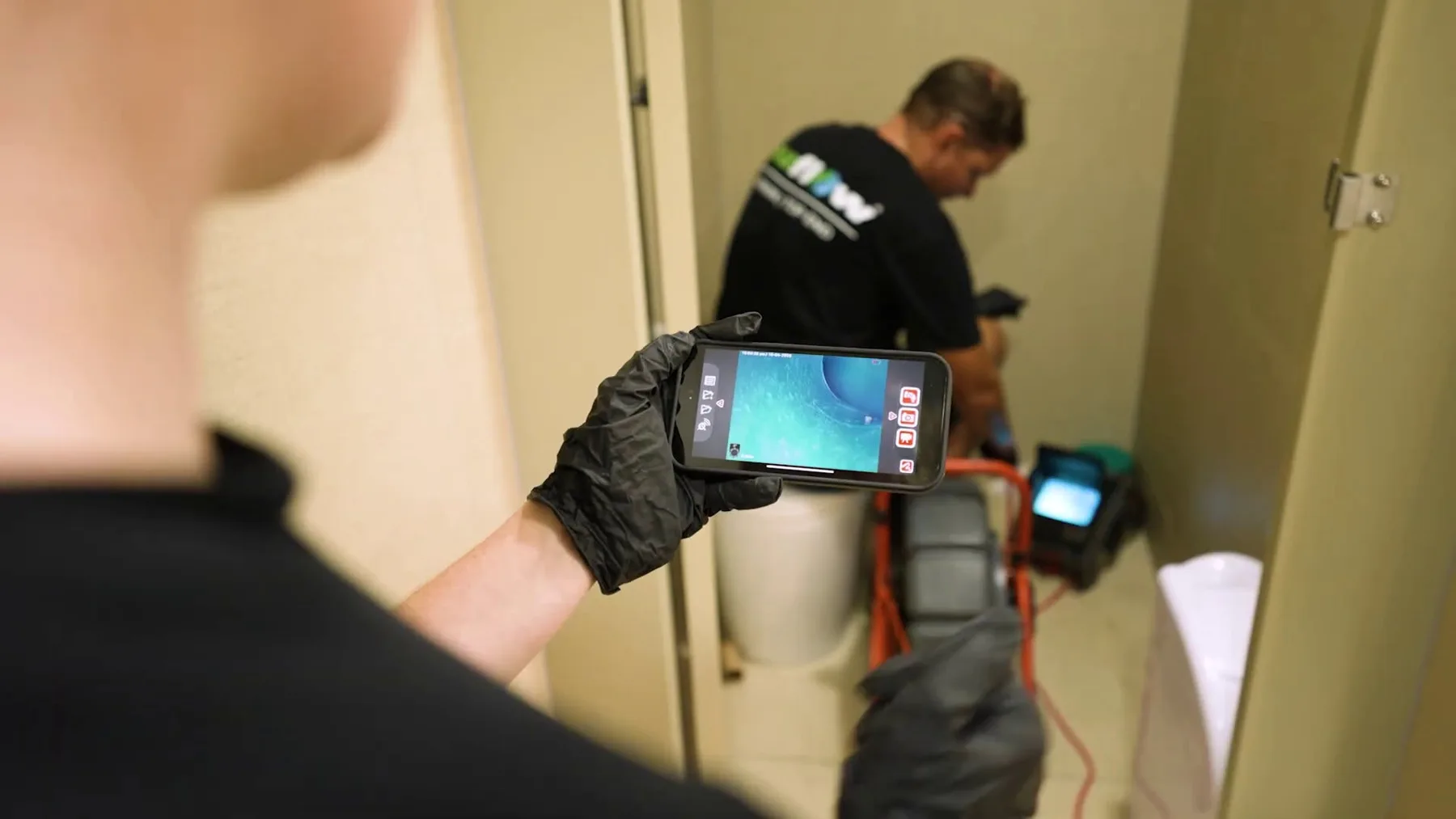 Technician viewing drain camera footage on a handheld screen
